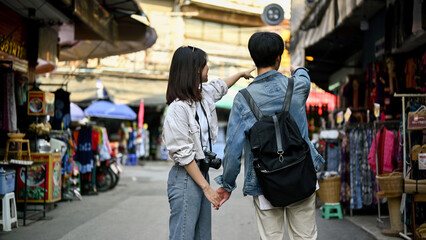 A tourist couple holding hands while sightseeing the Chiang Mai old town market together.