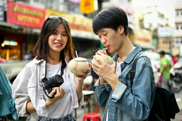 A tourist couple enjoying their fresh coconut drink at a Chinatown in Chiang Mai.