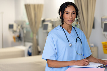 Unaltered portrait of smiling biracial female doctor wearing stethoscope in hospital reception