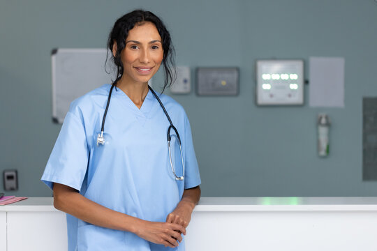 Unaltered portrait of smiling biracial female doctor wearing stethoscope at hospital reception