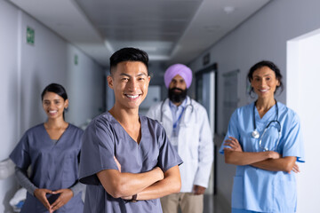 Group portrait of happy diverse male and female doctors standing in corridor at hospital