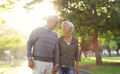 Senior couple, walking and holding hands outdoor at a park with love, care and support. A elderly man and woman in nature for a walk, quality time and communication for healthy marriage or retirement