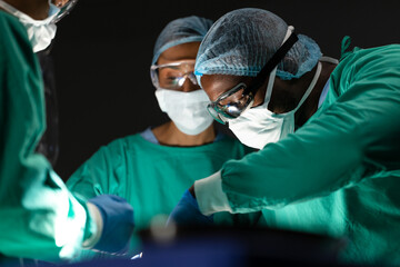 Diverse surgeons operating on patient in operating theatre at hospital