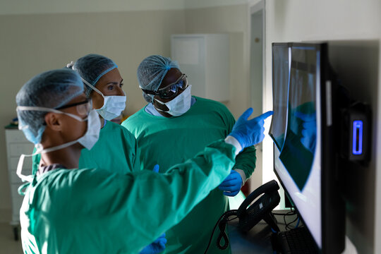 Diverse male and female surgeons looking at x-rays in operating theatre before surgery