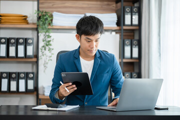 Fototapeta premium Businessman working at home with tablet and laptop computer and papers on desk.