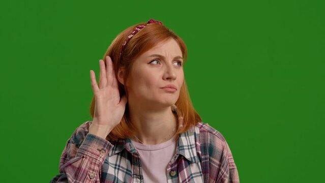 Woman, hand and ear for listening by green screen with confused face, thinking and attention by background. Girl, model and hearing for conversation, sound or gossip in studio portrait by backdrop