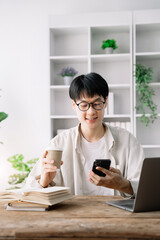 Happy student male using laptop computer, mobile phone, working freelance project online, sitting outdoors. Successful business. Asian student studying, learning language, online education concept