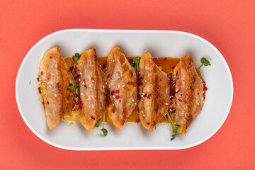 Plate of fried japanese gyoza dumplings on pink background