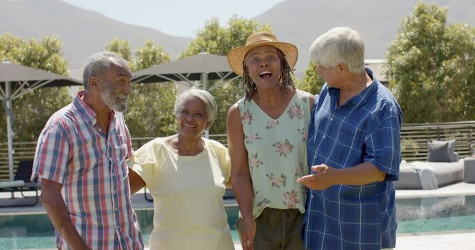 Happy diverse senior friends welcoming guest to sunny garden party, unaltered, in slow motion