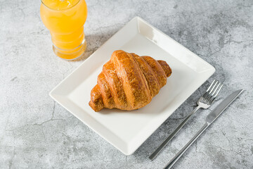 Croissant on white porcelain plate on light stone table
