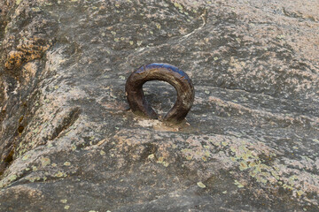 Large iron loop shackle in stone or rock. Old fastening of boats and ships when moored on the shore