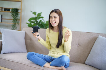 Obraz premium Happy&nbsp;Young Asian woman gamer controller video console playing&nbsp;holding hobby playful Online Video Game enjoyment eSport Cyber Games Internet &nbsp;victory celebration