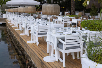 Summer terrace of Mediterranean restaurant, popular travel destination near sea with hipster tables and chairs. 