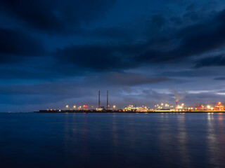 Fototapeta na wymiar Illuminated dock area of Dublin port at night, Dark dramatic sky. Night shot. Transportation industry, Import and export gate of the country.