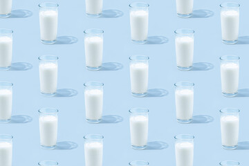 Glasses of dairy milk on pastel blue background with shadows and sun reflections. Concept of...