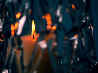 Burning orange candle in a glass mesh vase. Warm and cool color scheme. Abstract art.
