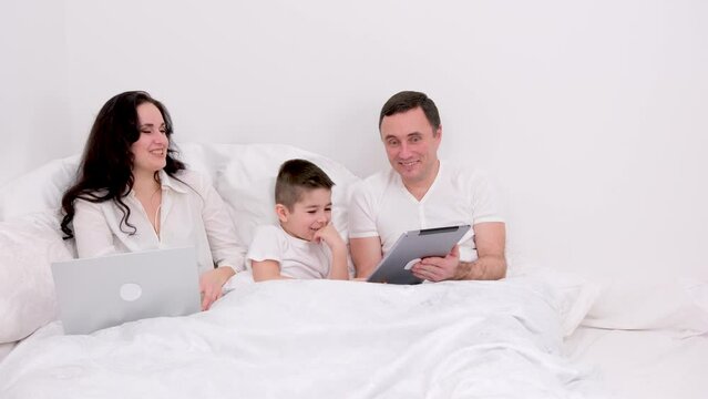 man woman boy spend time together in bed holiday vacation chat have fun relax look at tablet real people live conversation love at home happiness joy success in gadgets place for ad text happy family