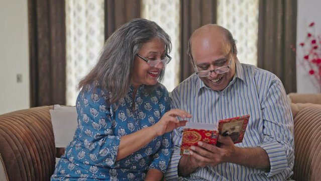 Happy Old Indian couple laughing and going through photo album