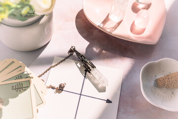 Fototapeta premium Gemstones for esoteric spiritual practice. Rock crystal pendulum on the table. Divination with a pendulum.
