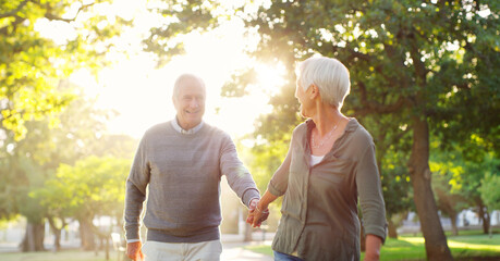 Walking, holding hands and a senior couple outdoor at a park with a love, care and support. Elderly man and woman in nature to follow on a walk, quality time and happy marriage or healthy retirement