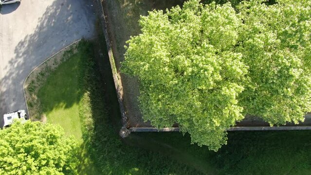 Ramparts of a medieval city seen from above with its trees with a car passing giving the top start