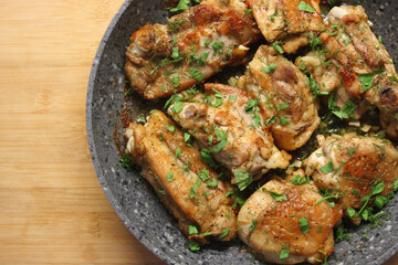 Top view of frying pan with fried chicken breast, herbs and garlic