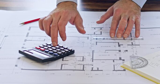 Engineer hands make construction calculations about latest building plan using calculator. Employee uses ruler for measuring length of details on drawing