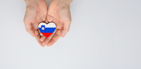 The national flag of Slovenia in the shape of a heart in the hands. Flat lay, copy space.