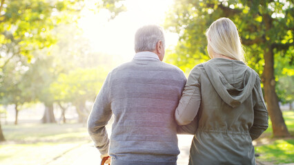Senior man, daughter and walking outdoor at a park with love, care and support for health and wellness. A elderly male and woman of family in nature for a walk, quality time and healthy retirement