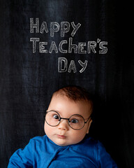 Fototapeta na wymiar A beautiful little baby with glasses, concept. Background is chalkboard with the inscription of Happy Teacher's Day.