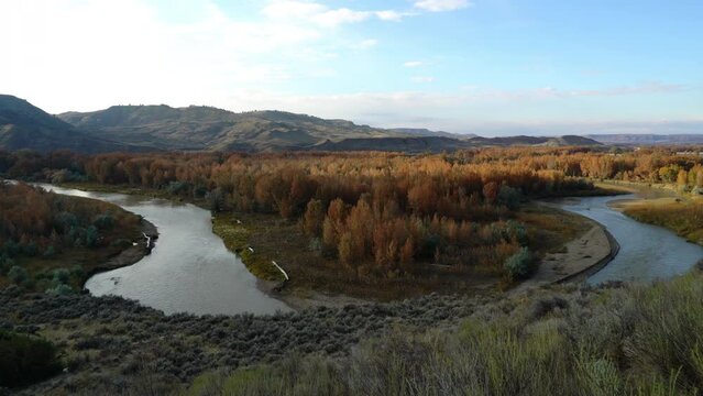 Evening sun flows over orange fall foliage of river valley