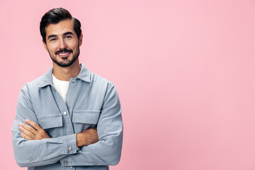 Portrait of a stylish brunette man with a beard looking into the camera on a pink background in a white T-shirt and jeans smile and joyful emotion on his face, copy space