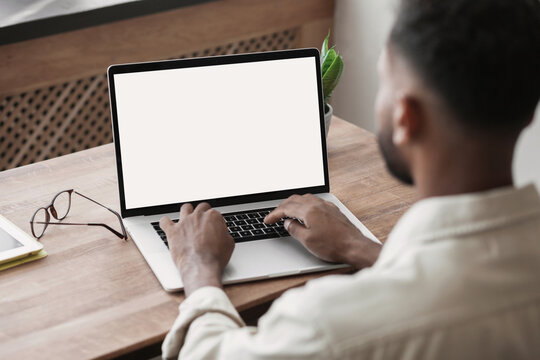 Young man using laptop computer with blank empty mockup screen. Business man working at home. Freelance, student lifestyle, e-learning, shopping online, web site, technology concept