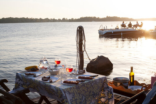 Food and wine on table by lake during sunset