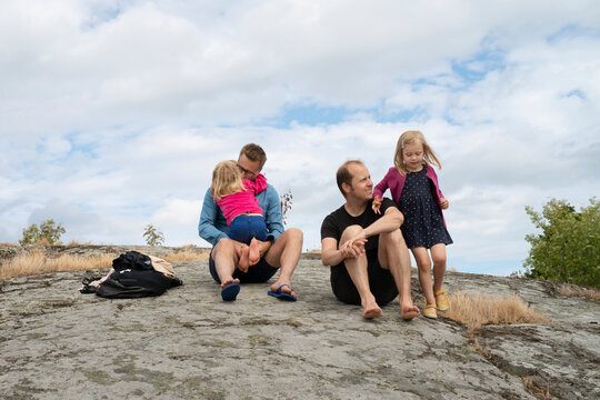 Family sitting on rock under clouds