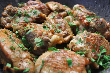 Closeup view of fried chicken with herbs and garlic on frying pan