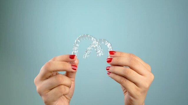 Young Asian Indian woman holding removable invisible aligner, also known as invisalign or  clear aligner