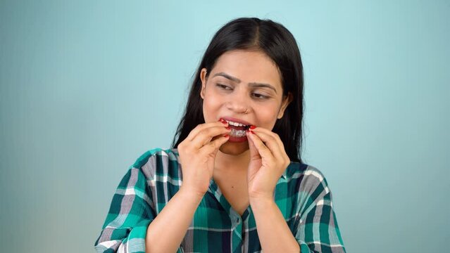 Young Asian Indian woman holding removable invisible aligner, also known as invisalign or  clear aligner