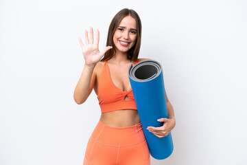 Young beautiful sport woman going to yoga classes while holding a mat isolated on white background counting five with fingers