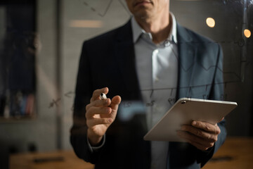 Portrait of successful businessman in office. Man writing on the glass board in office..