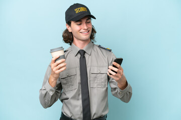 Young safeguard man isolated on blue background holding coffee to take away and a mobile