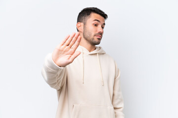 Young caucasian man isolated on white background making stop gesture and disappointed