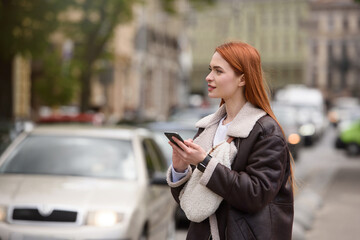 Fototapeta premium happy woman communicates with friends via video link outdoors on an old town street