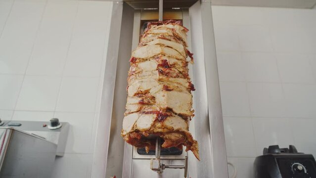 Cooking meat on a skewer . Meat on a spit . Cooking doner kebab or shawarma on a rotating vertical spit. Traditional street fast food. Large Doner skewer spinning in a local restaurant