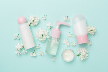 Composition with cosmetic bottle and flowers on color background, top view