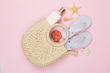 Beach bag with childish flip flops and sun protection on color background, top view