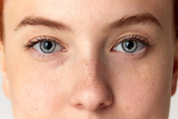 Cropped portrait with eyes of young girl, woman, girl with blue eyes over white background. Close...