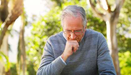 Depression, park and senior man crying while sitting on a bench thinking on mental health problem....