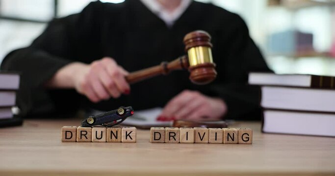 Judge knocks gavel on background of words drunk driving. Judicial practice on deprivation of driver license for driving intoxicated