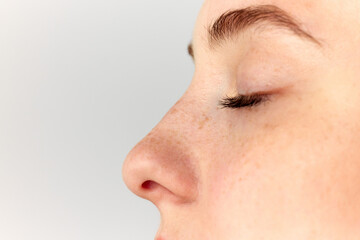 Young woman, girl demonstrating nose after, before surgery over white studio background. Side view....